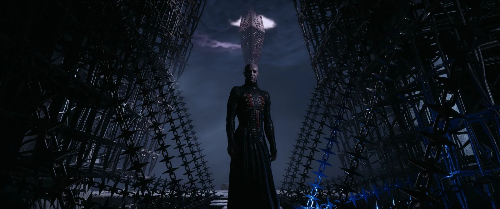 Pinhead standing between walls of barbed chain, with Leviathan's spire rising into the clouds above him